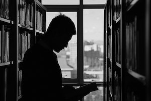 Sihouette photo of man in library. Photo by Pixabay.