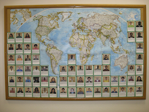 bulletin board with world map with photos/bios of tutors and staff of a learning center with pins placd on the map where each person was born.